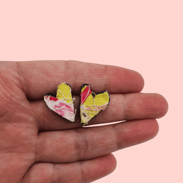 a pair of small heart shaped stud earrings. pink and yellow textile created with scraps of fabric. 