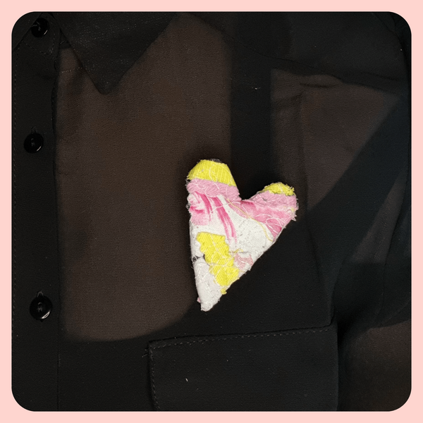 heart shaped fabric brooches  created using scrap fabrics. pinks and yellows with a black back. styled on a black shirt