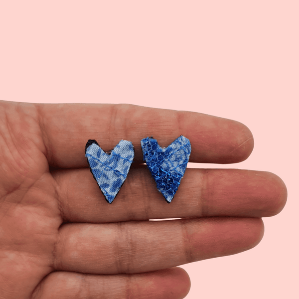 a pair of small heart shaped stud earrings. blue textile created with scraps of fabric. 