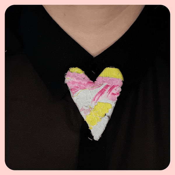 heart shaped fabric brooches  created using scrap fabrics. pinks and yellows with a black back. styled on a black shirt collar