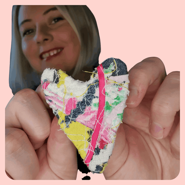 a white woman holding up a fabric brooch