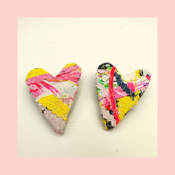 Two heart shaped fabric brooches  created using scrap fabrics. pinks and yellows with a black back.
