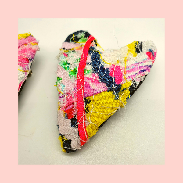 heart shaped fabric brooches  created using scrap fabrics. pinks and yellows with a black back.