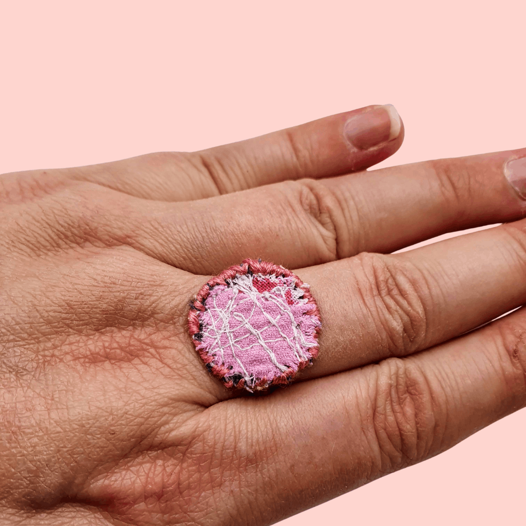 A circle fabric ring pink fabric with pink decorative stitching around the edge.